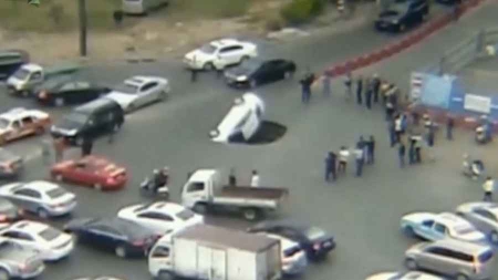 Une voiture happée par un trou en pleine route